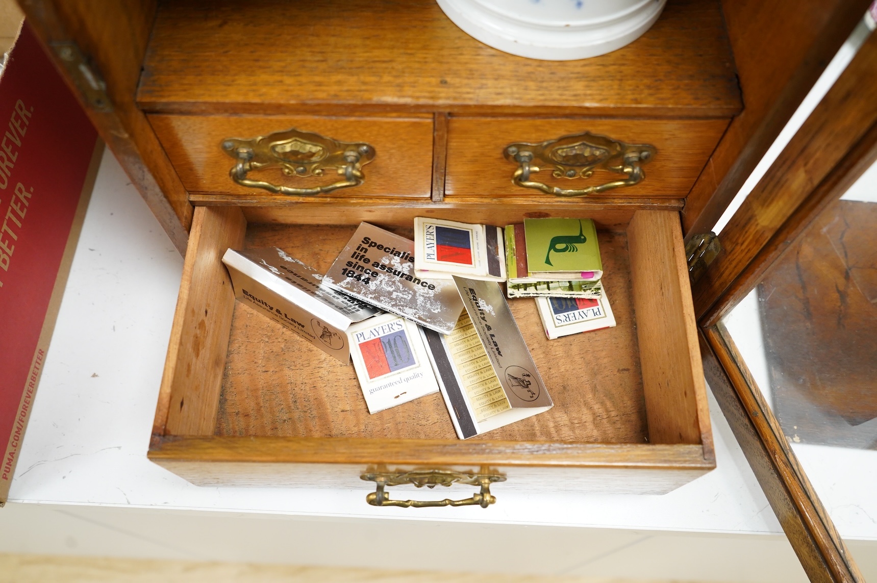 An Edwardian oak smoker's cabinet, with Doric blue and white tobacco jar and cover, 38cm high x 29.5cm wide.